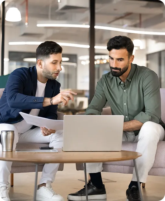 Two colleagues reviewing information together on a laptop in a modern office