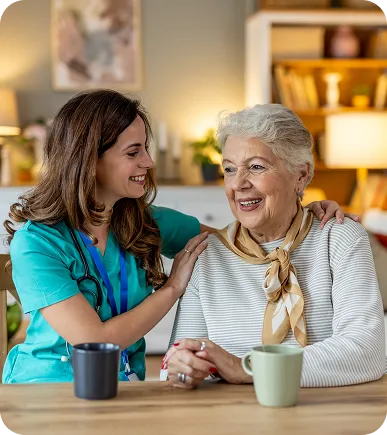 Caregiver smiling with an older woman at a kitchen table