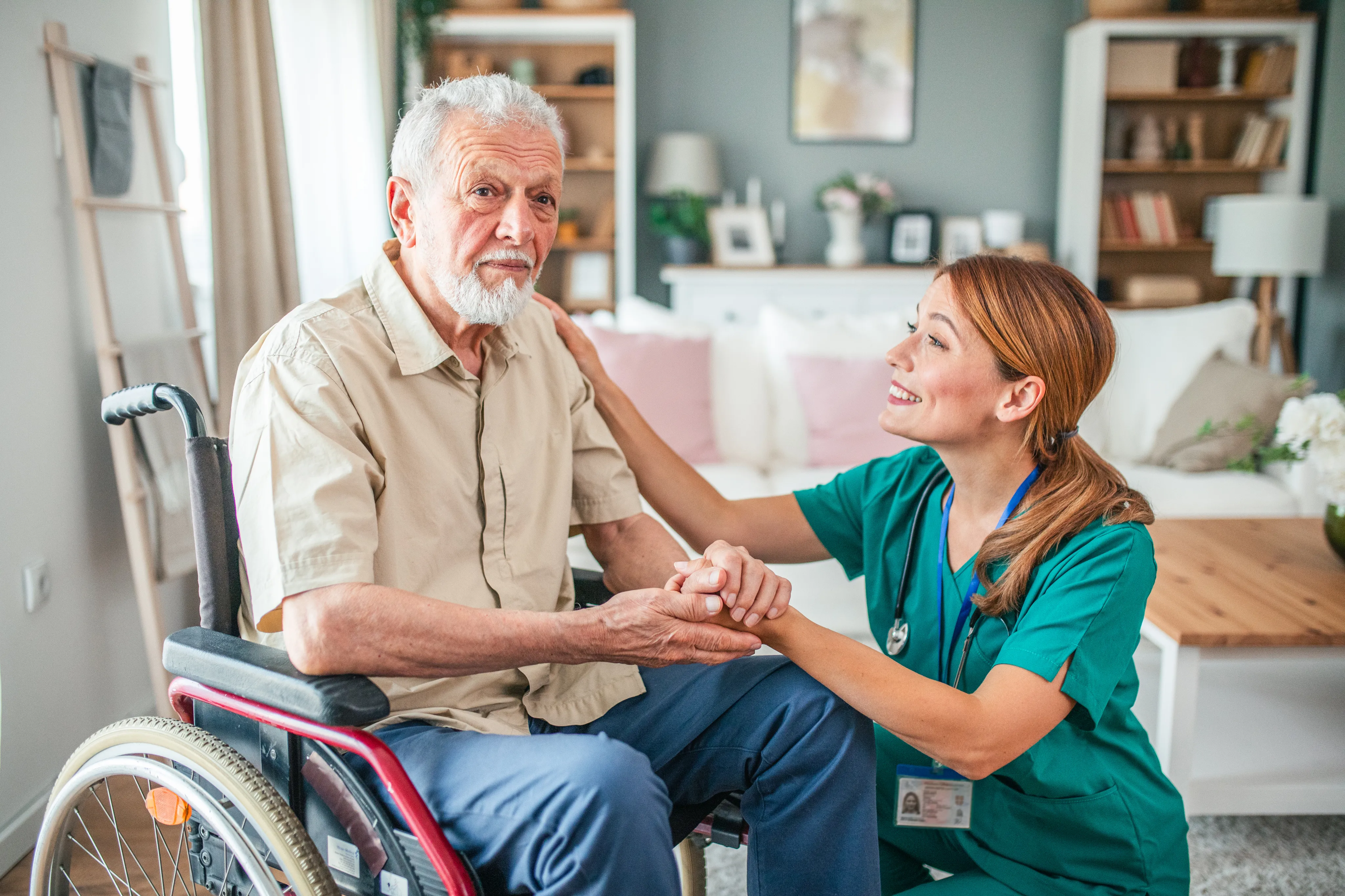 A nurse holding hands with an elderly man seated in a wheelchair