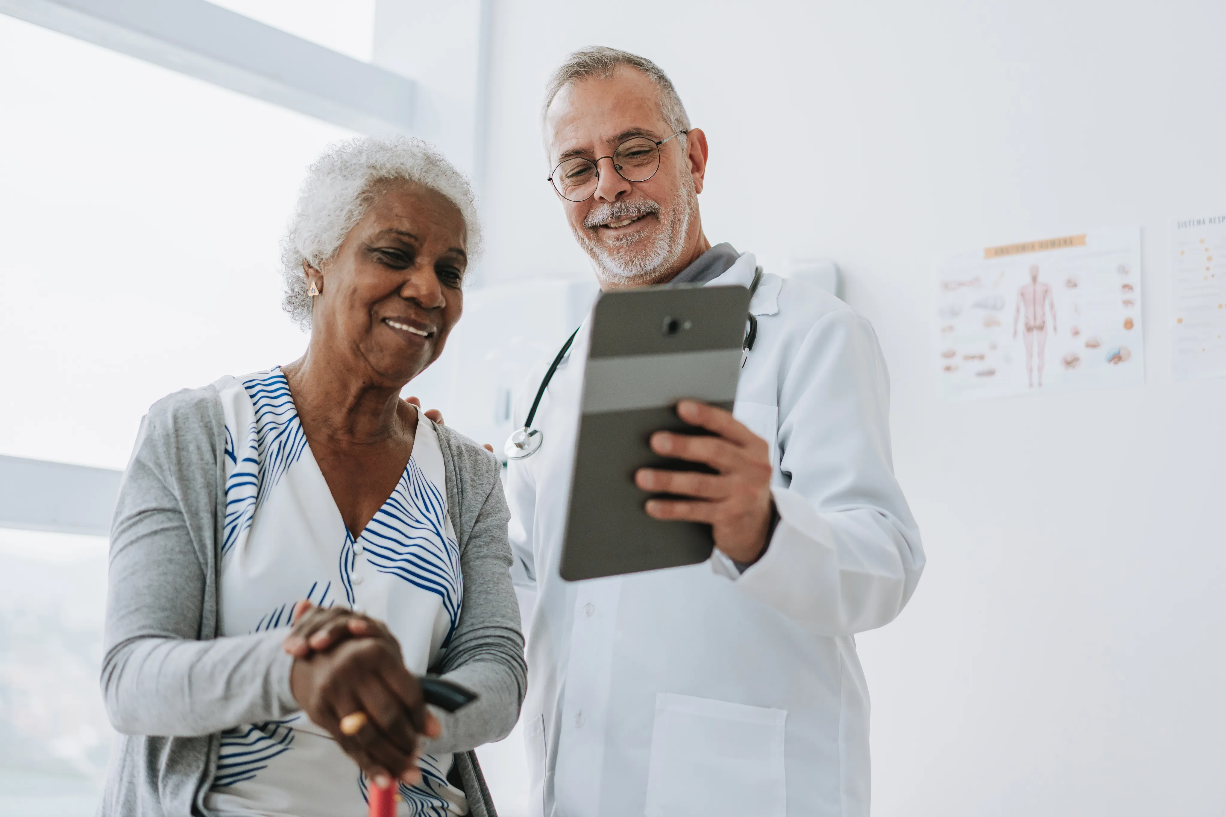 A doctor reviewing information on a tablet with an elderly patient