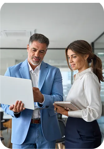 Two business professionals reviewing information together on a laptop and tablet in an office